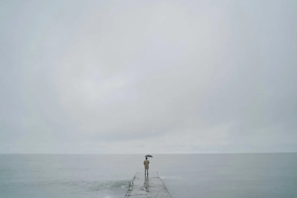 Mann auf Steg der auf das Wasser schaut